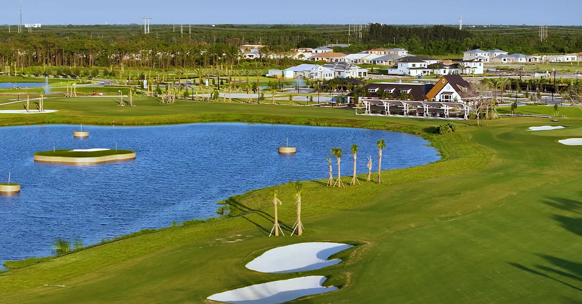 This image shows aerial view of golf course with lake and clubhouse with clear visibility of course features, landscaping, and built structures.